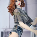 Luluella Sex Doll 168 cm IronTech Doll TPE en short denim et t-shirt gris, cheveux ondulés.