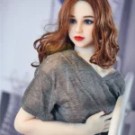 Luluella Sex Doll 168 cm IronTech Doll TPE en pose assise, cheveux châtain ondulés, top gris.