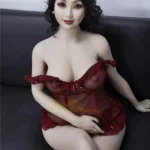 Luluva Sex Doll 160 cm IronTech Doll TPE en robe rouge, assise sur un canapé noir.