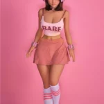 Lumabelle Sex Doll 153 cm IronTech en jupe rose, débardeur "Babe", écouteurs et chaussettes hautes.