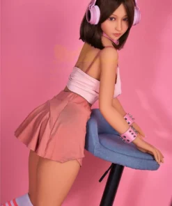 Lumabelle Sex Doll 153 cm IronTech Doll en jupe rose, pose inclinée sur tabouret bleu.