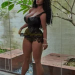 Luméa Sex Doll 158 cm IronTech en robe noire, posée debout près d'une fenêtre.