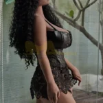 Luméa Sex Doll 158 cm IronTech en tenue noire, posée de profil près d'une fenêtre.