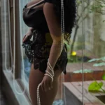 Luméa Sex Doll 158 cm IronTech Doll TPE en lingerie noire, posant près d'une fenêtre.
