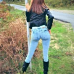 Lumelia Sex Doll 165 cm IronTech Doll TPE en jean et veste noire, posée de dos en extérieur.