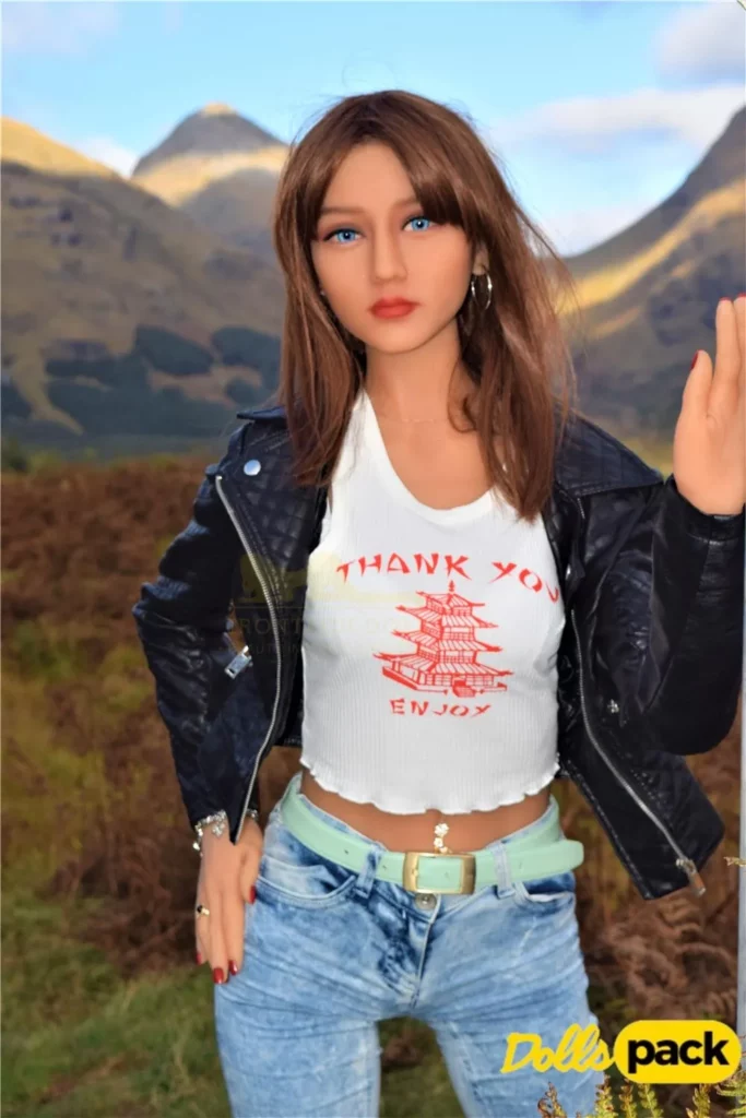 Lumelia Sex Doll 165 cm IronTech en veste noire, jean bleu, posée devant des montagnes.