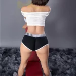 Lumière Sex Doll 159 cm IronTech Doll TPE en short noir, vue de dos sur banc.