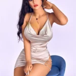 Lunara Sex Doll 164 IronTech en robe argentée, assise sur un tabouret bleu, pose séduisante.