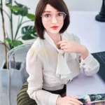 Lunaya Sex Doll 159 cm IronTech, assise, chemisier blanc, jupe verte, lunettes, ambiance bureau.