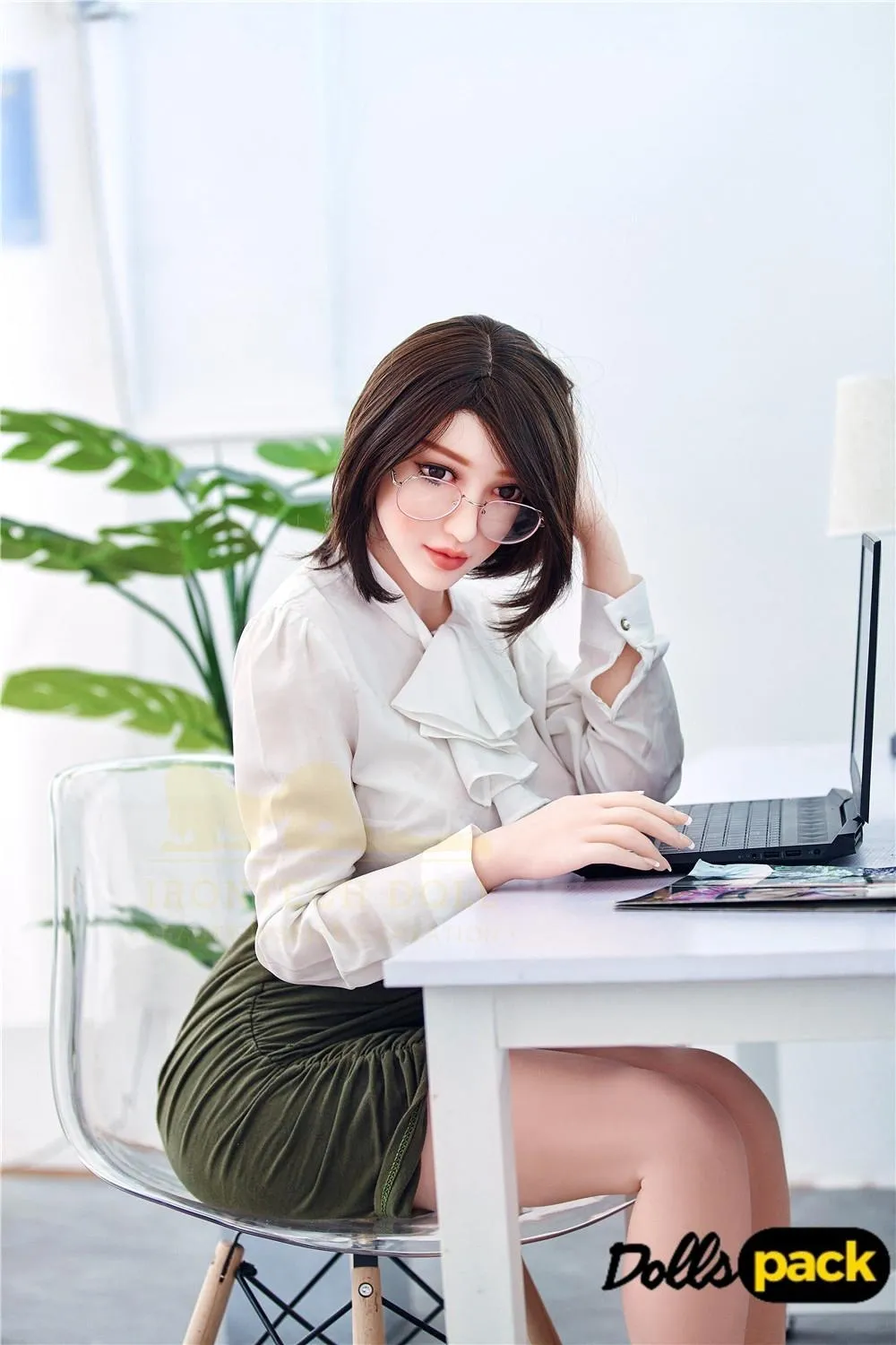 Lunaya Sex Doll 159 cm IronTech, assise à un bureau, chemisier blanc, jupe verte.