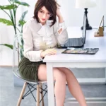 Lunaya Sex Doll 159 cm IronTech Doll TPE assise au bureau, lunettes, chemisier blanc.