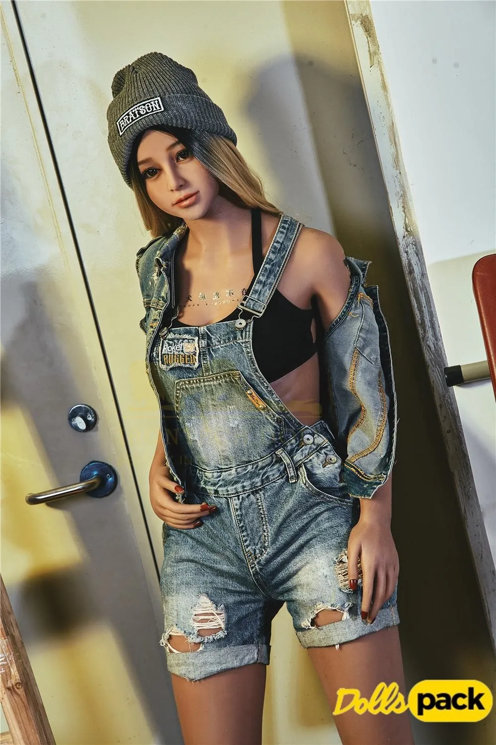 Lunia Sex Doll 163 cm IronTech en salopette denim et bonnet gris, pose décontractée.