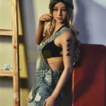 Lunia Sex Doll 163 cm IronTech, debout en salopette jean, bonnet gris, tatouage visible.