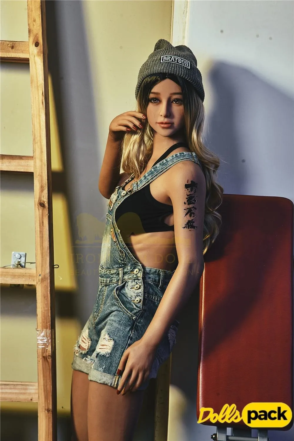 Lunia Sex Doll 163 cm IronTech, debout en salopette jean, bonnet gris, tatouage visible.