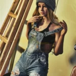 Lunia Sex Doll 163 cm IronTech en salopette denim, pose décontractée près d'une échelle.