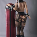 Lylia Sex Doll 158 cm IronTech Doll TPE debout, dos nu, tenue sexy, appuyée sur un sac de frappe.