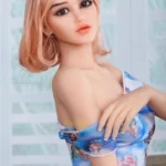 Lylia Sexy 165 cm IronTech Doll TPE en pose assise, regard vers l'avant, cheveux blonds courts.
