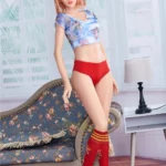 Lylia Sexy 165 cm IronTech Doll TPE debout, pose élégante, tenue colorée, intérieur lumineux.