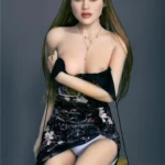 Maribel Sex Doll 165 cm IronTech posée assise, robe noire florale, cheveux longs bruns.