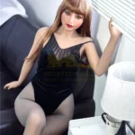 Mirabella Sex Doll 163 cm IronTech Doll en body noir, assise sur un canapé, regard vers la fenêtre.