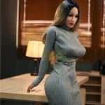 Mirabelle Sex Doll 153 cm IronTech en robe grise moulante, posée debout près d'une table.