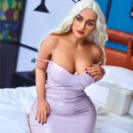 Nimaya Sex Doll 156 cm IronTech en robe moulante blanche, posée à genoux sur un lit.