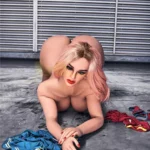 Ravelya Sex Doll 160 cm IronTech, posée à quatre pattes avec vêtements colorés au sol.