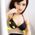 Séraphine Sex Doll 155 cm IronTech Doll TPE en bikini noir dans une baignoire avec pétales jaunes.