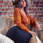 Velena Sex Doll 156 cm IronTech en tenue bohème, chapeau de paille, fond mur de briques.