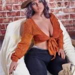 Velena Sex Doll 156 cm IronTech en tenue cowgirl, assise sur un fauteuil, fond de briques.