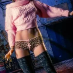 Zella Sex Doll en culotte léopard et bas porte un haut rose et des lunettes.