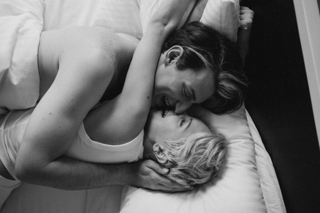 Couchés dans un lit, un couple rit. Leur complicité symbolise le bien-être émotionnel et la sérénité que les Real Dolls peuvent apporter.
