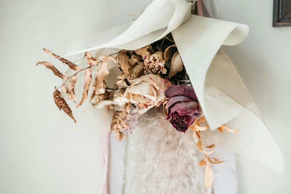 Bouquet de roses séchées et fanées enveloppées dans du papier blanc représentant l'impact psychologique de la dysfonction érectile