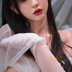 Shangrila Sex Doll 153 cm IronTech Doll en pose assise, cheveux noirs, drap blanc transparent.